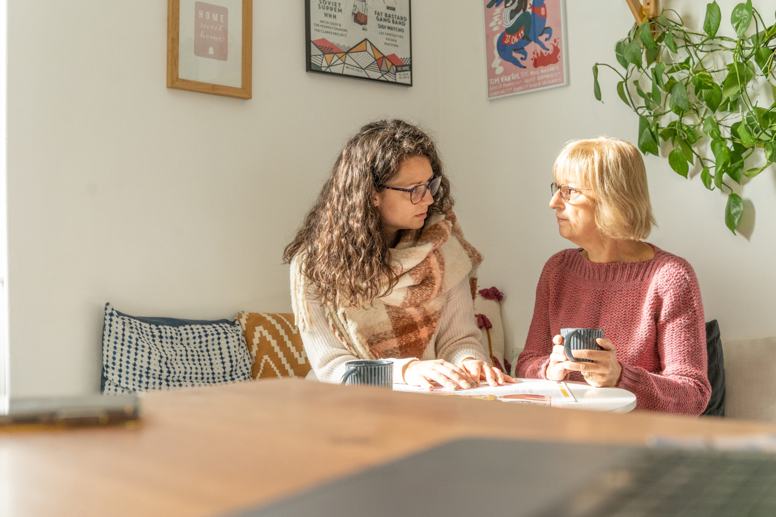 deux femmes assises échangent avec un carnet et une tasse de café